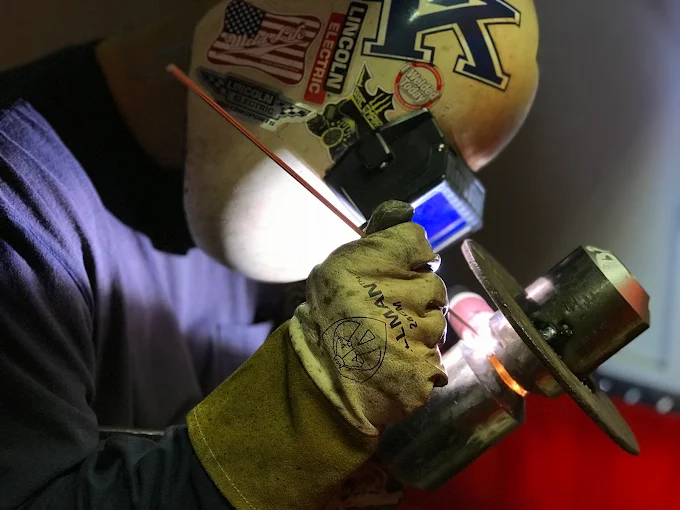 KWI welding student in a Lincoln Electric helmet working on a weld