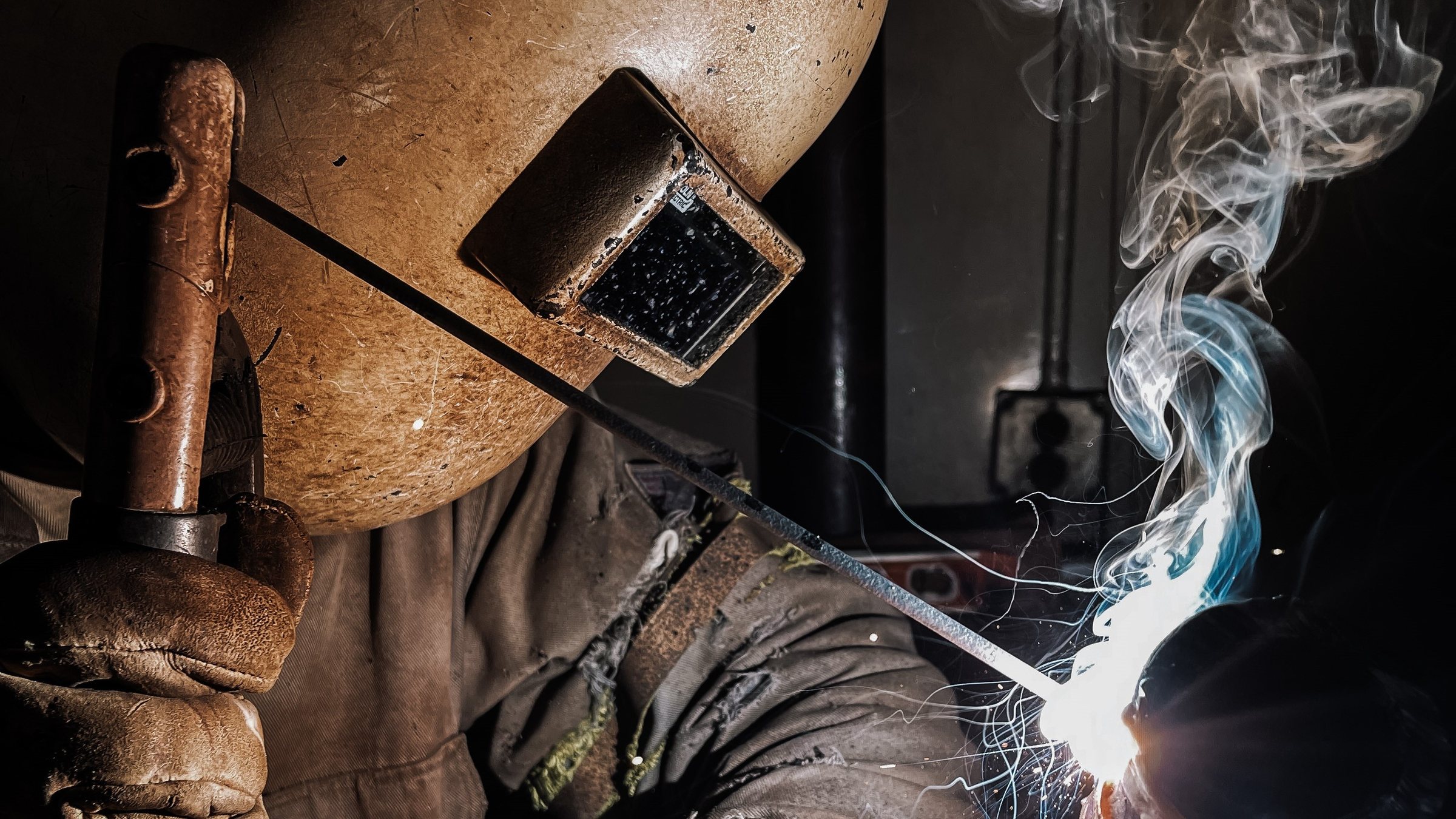 A KWI student striking an arc, smoke rising off the weld